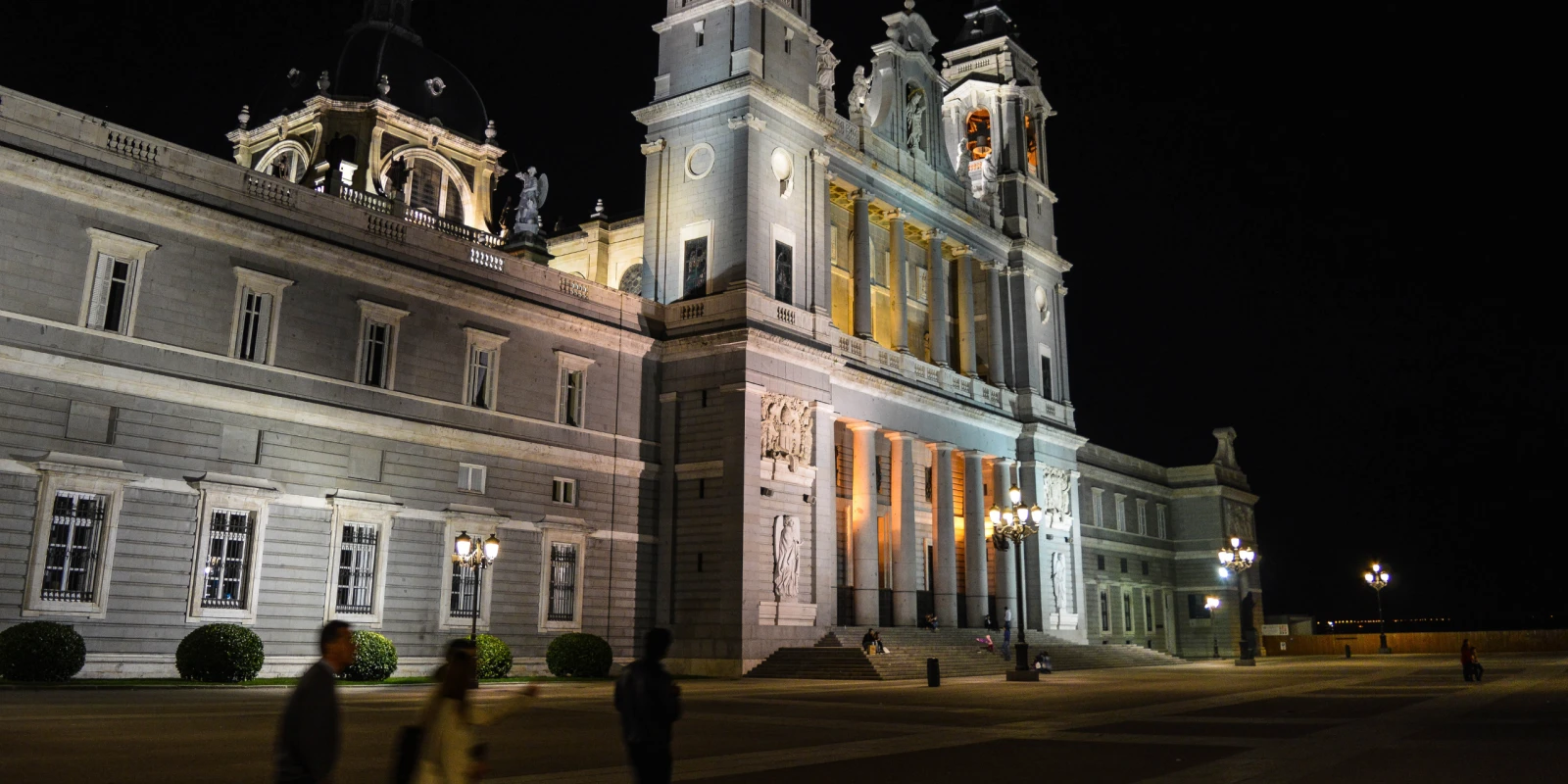 Almudena Cathedral in Madrid lit up at night beside the Plaza de la Armería
